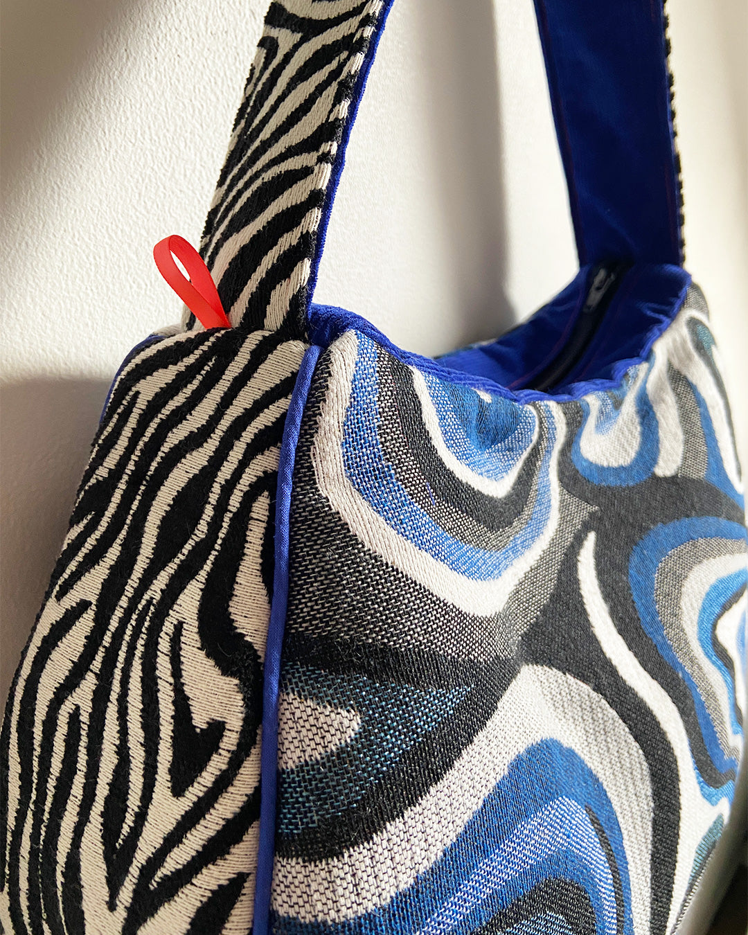 unieke, handgemaakte en stijlvolle schoudertas van PIEKS creations met grafisch patroon in zwart, wit en blauw en zebraprint aan de zijkant - close up