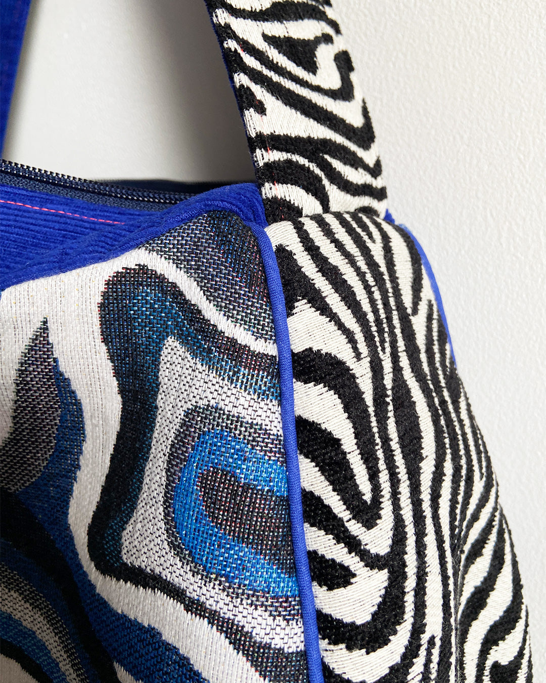unieke, handgemaakte en stijlvolle schoudertas van PIEKS creations met grafisch patroon in zwart, wit en blauw en zebraprint aan de zijkant - detail zijkant