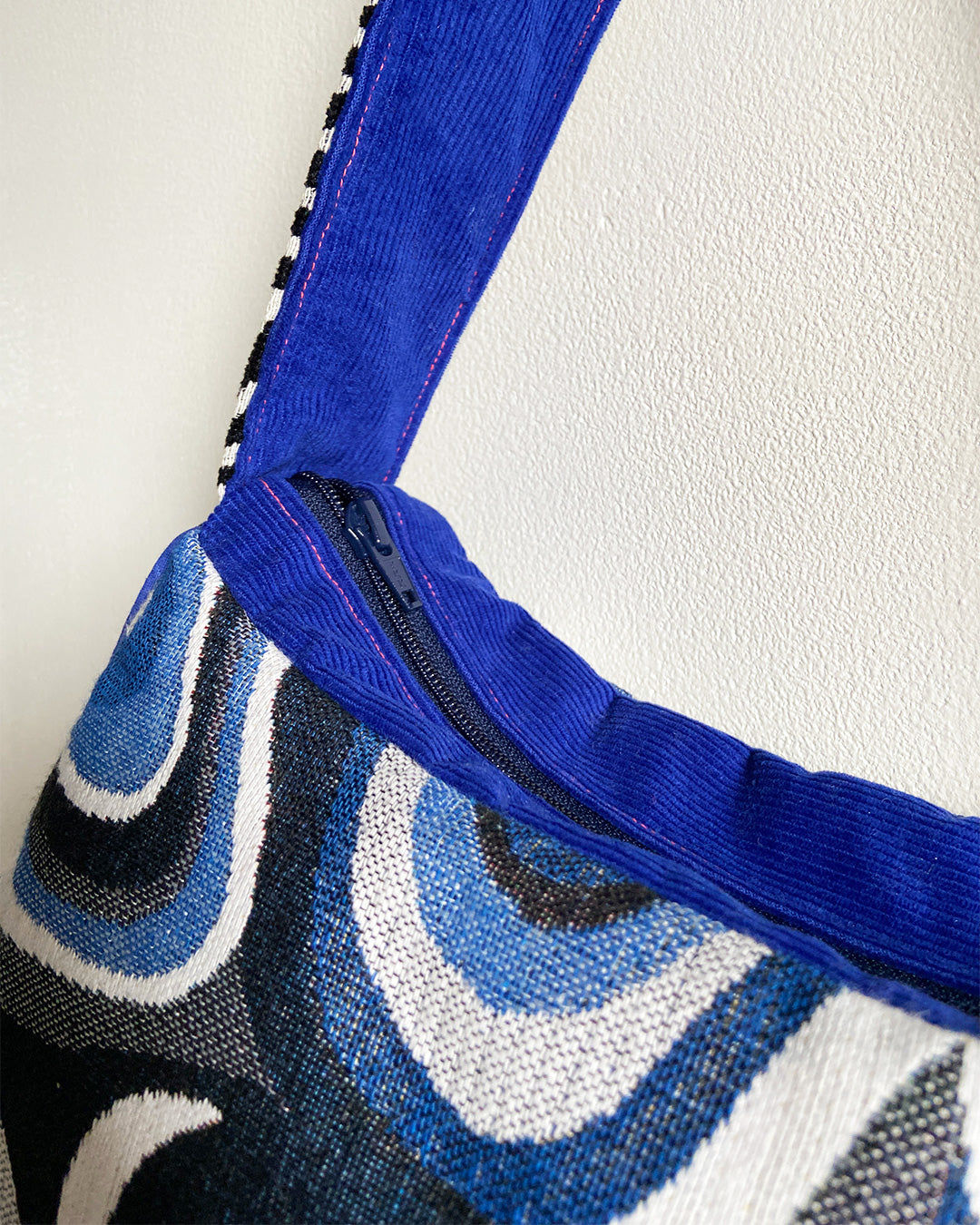 unieke, handgemaakte en stijlvolle schoudertas van PIEKS creations met grafisch patroon in zwart, wit en blauw en kobalt blauwe babyrib als afwerking - rits