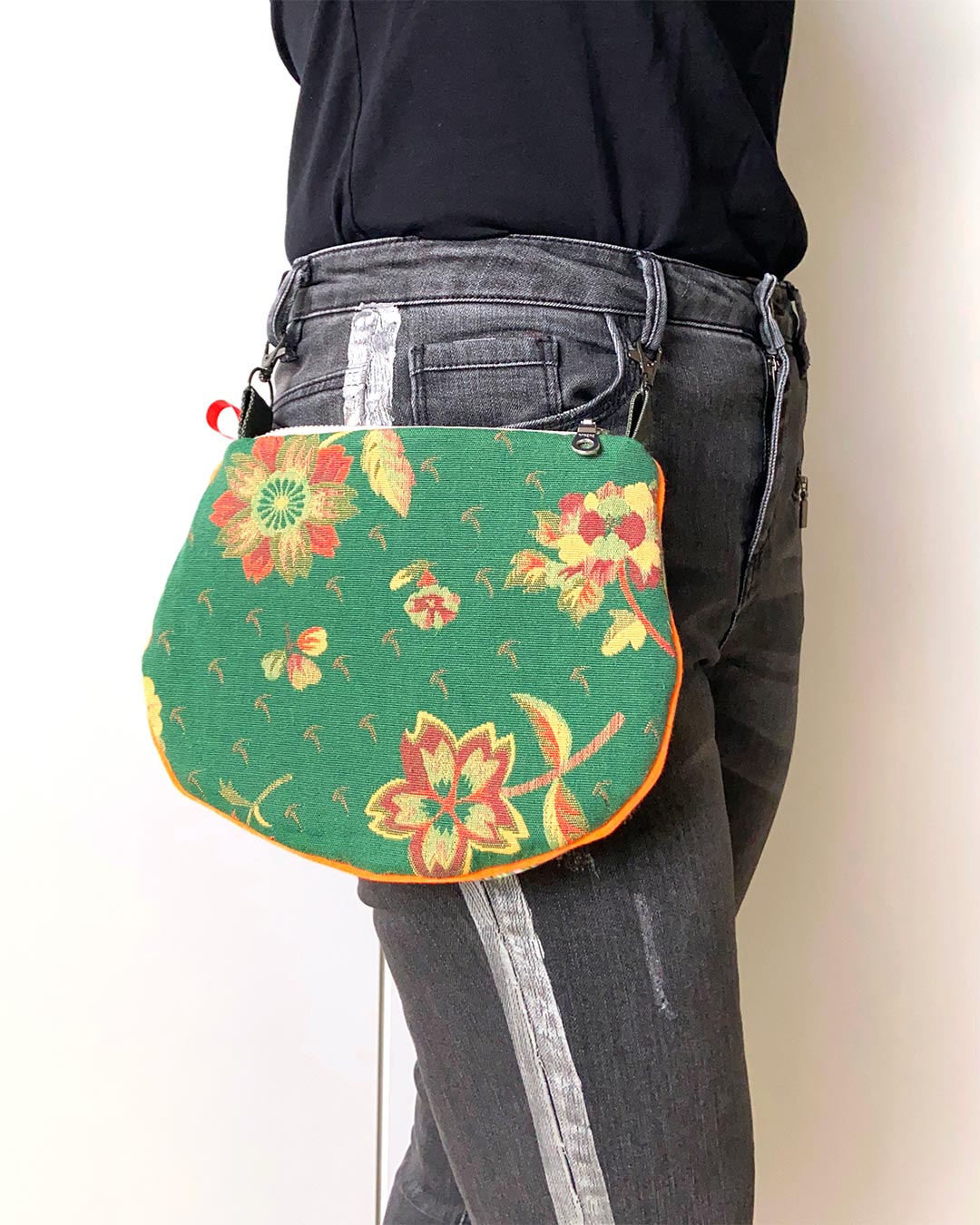 uniek, handgemaakt en kleurrijk handtasje van PIEKS creations groen met bloemen en streepjes en oranje accent - aan de broek vastgemaakt