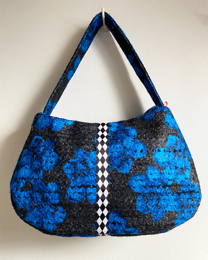 unieke, handgemaakte en stijlvolle wollen schoudertas van PIEKS creations in zwart met grote donkerblauwe bloemen en een stoere band met een grafisch zwart wit ruit  - achterkant