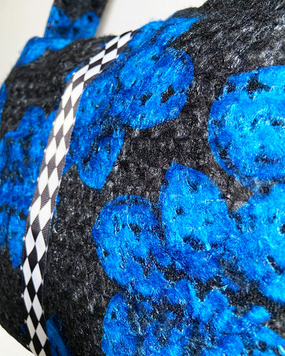 unieke, handgemaakte en stijlvolle wollen schoudertas van PIEKS creations in zwart met grote donkerblauwe bloemen en een stoere band met een grafisch zwart wit ruit  - detail van de stof