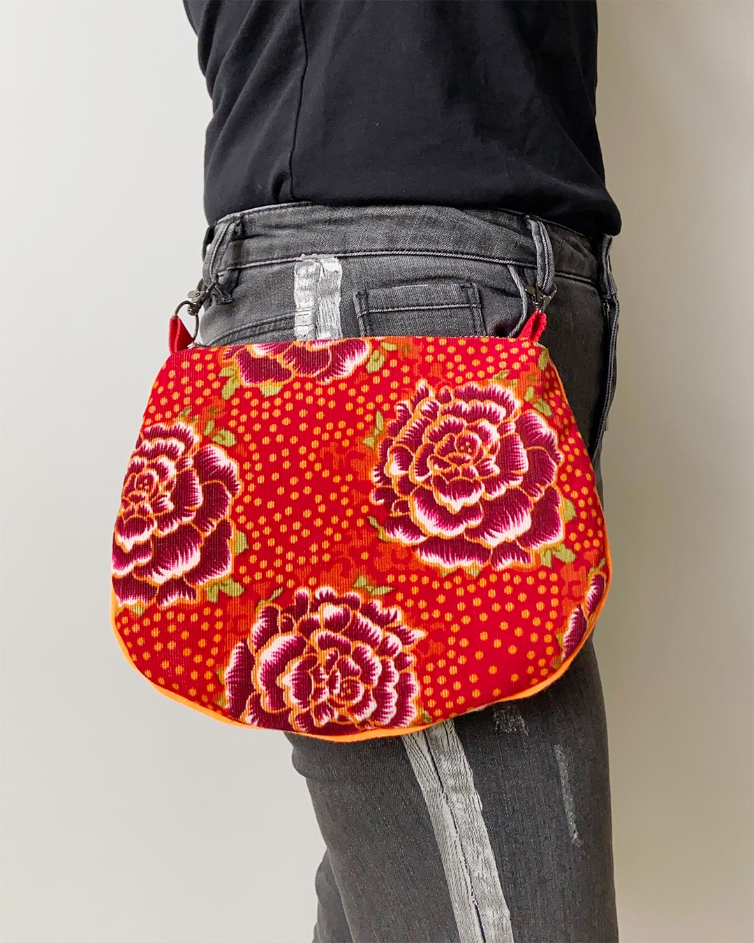 uniek, handgemaakt en kleurrijk handtasje van PIEKS creations met bloemenpatroon in oranje kleuren - aan de broek vastgemaakt