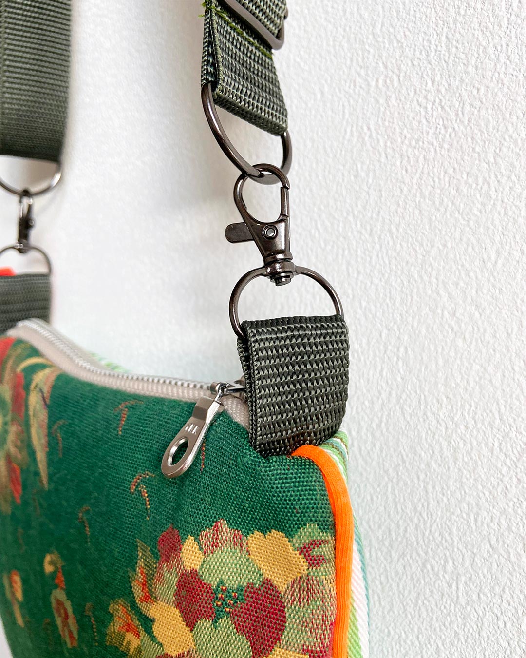 uniek, handgemaakt en kleurrijk handtasje van PIEKS creations groen met bloemen en streepjes en oranje accent - detail gesp